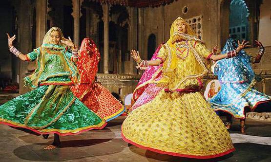 Women dressed in flowing lehengas twirling gracefully during a Ghoomar dance performance, celebrating culture and festivity.