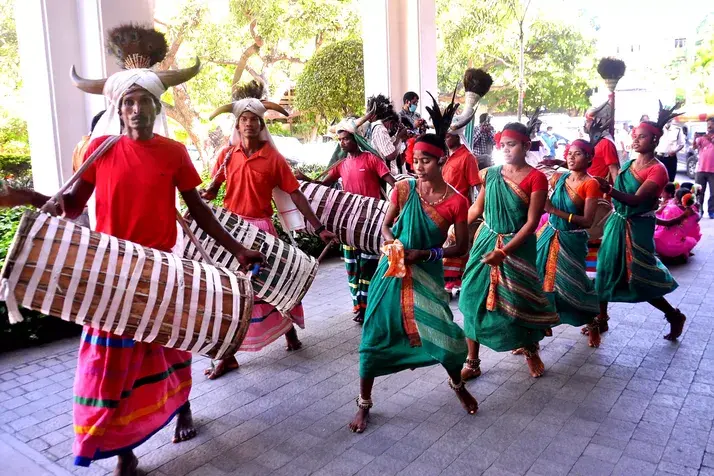 A tribal group performing the Dhimsa dance, dressed in traditional attire, moving together in perfect synchronization.