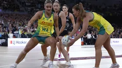 Australian netball team players defending a pass during a match, highlighting their agility and teamwork.