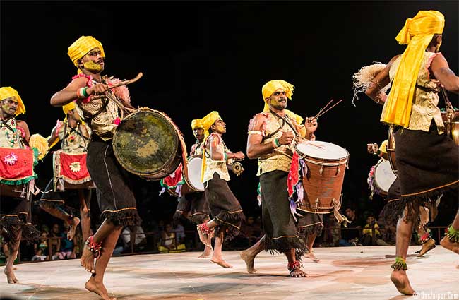 A group of performers in traditional attire performing Dollu Kunitha, a vibrant Karnataka folk dance