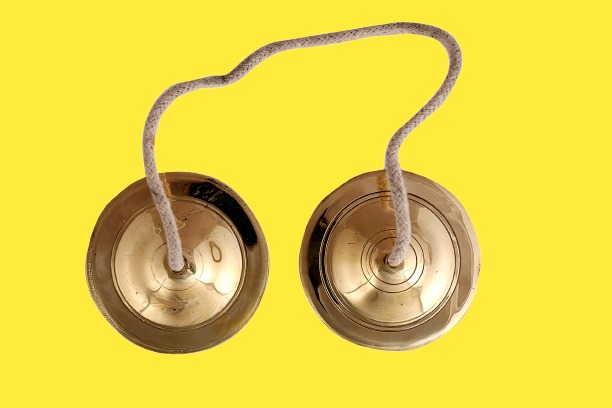 Close-up of a Kamsale, a traditional percussion instrument from Karnataka, featuring a pair of cymbals with intricate designs, used in the rhythmic performances of the Kamsale folk dance