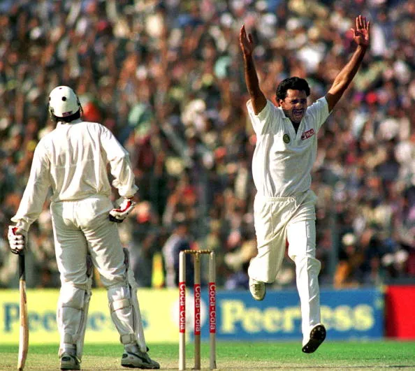 Javagal Srinath, in full cricket gear, captured mid-delivery while bowling a fast ball on the cricket field.