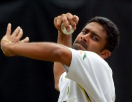 Anil Kumble in action, wearing the Indian cricket team's whites, preparing to deliver a leg-spin bowling during a Test match