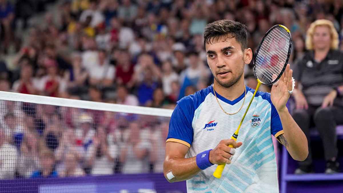 Lakshya Sen is seen smiling brightly after a match victory, wearing a vibrant sports jersey. At just 16 years old, he made history by winning his first BWF Super Series title.