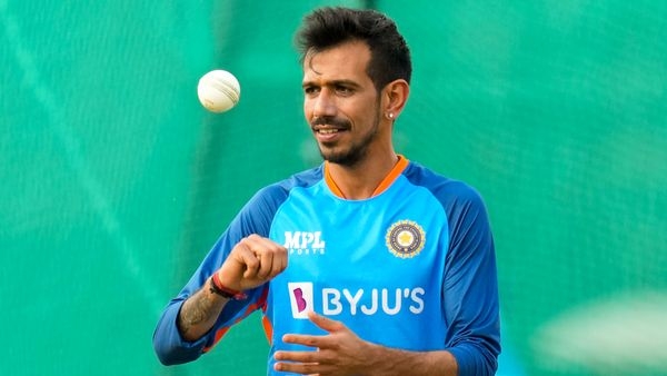 Yuzvendra Chahal smiling and standing in the Indian blue ODI jersey, holding the cricket ball ready for his spin delivery.