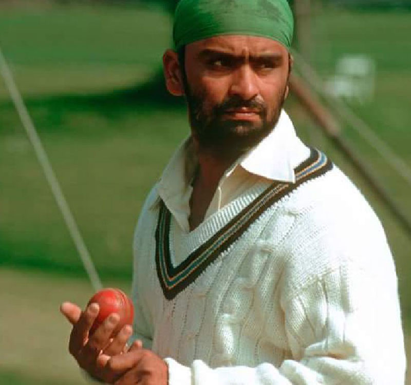 Bishan Singh Bedi, wearing the classic Indian cricket whites, preparing to bowl with his graceful left-arm spin action.