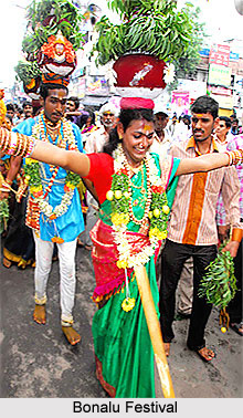 A Bonalu dancer in traditional attire, holding a decorated pot (Bonalu) on her head while performing a circular dance with devotional fervor. The background hints at a festive atmosphere with a temple setting.