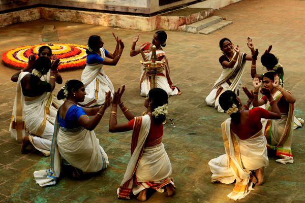 A group of women performing Thiruvathirakali in a circle, clapping hands rhythmically during a traditional dance