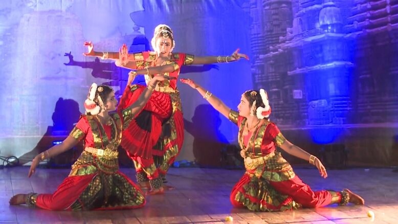 A vibrant group of women performing Kalapam dance, clapping their hands and moving in rhythm. The dancers are in colorful traditional outfits, with one hand raised, and the atmosphere is joyful and energetic. 